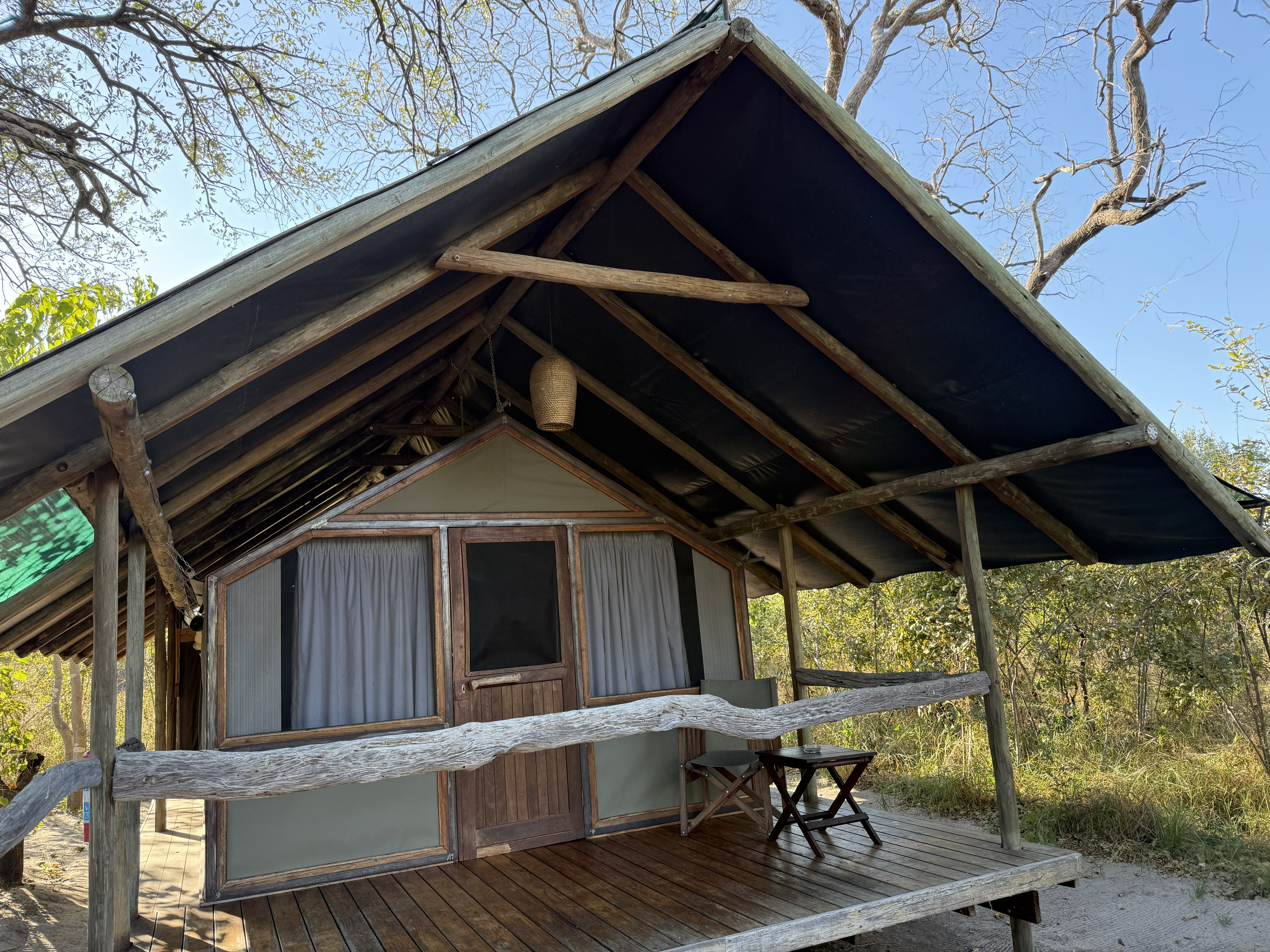 Our tent — canvas and timber on a raised deck under the trees, a camp chair on the veranda. Glamping, in the honest sense of the word: the wild at arm's length, and a real bed