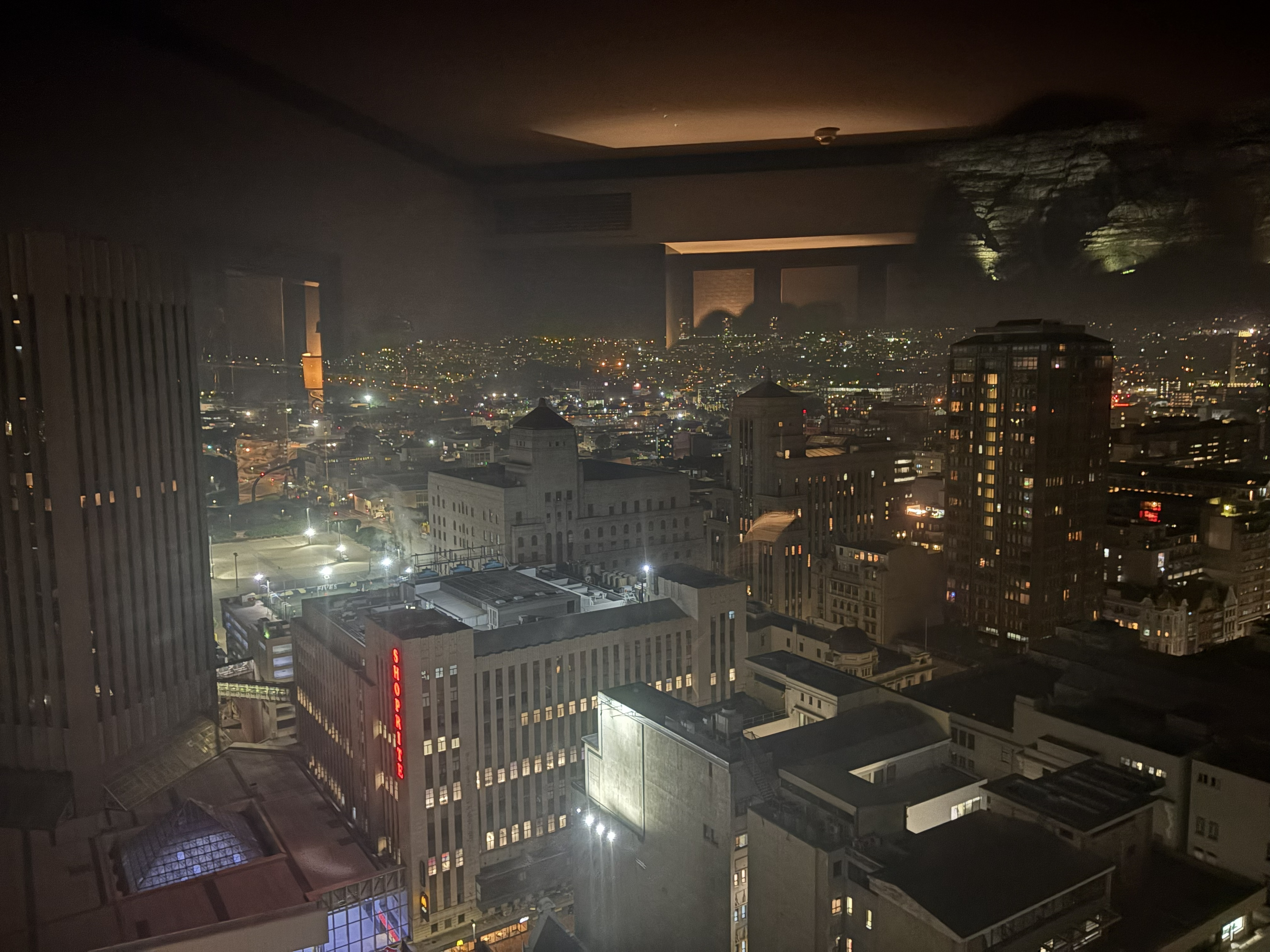 The same view a few hours and six floors later — Bonnie's, from the twenty-sixth — the city gone fully to night, the Shoprite sign glowing, the mountain floodlit and looming o